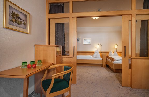 Komfortables Familienzimmer mit Glasabtrennung, zwei Einzelbetten und Holzmöbeln.