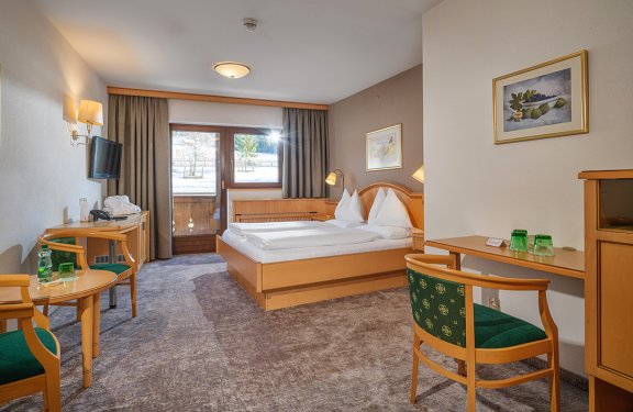 Helles Doppelzimmer mit Balkon, Sitzecke und Blick auf die Winterlandschaft.