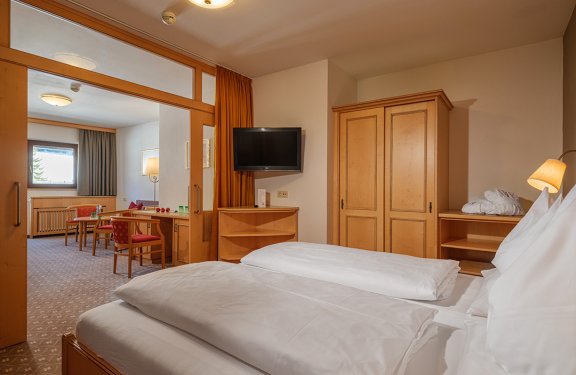 Komfortable Suite mit Schlafzimmer, Wohnbereich und praktischer Glas-Schiebetür.