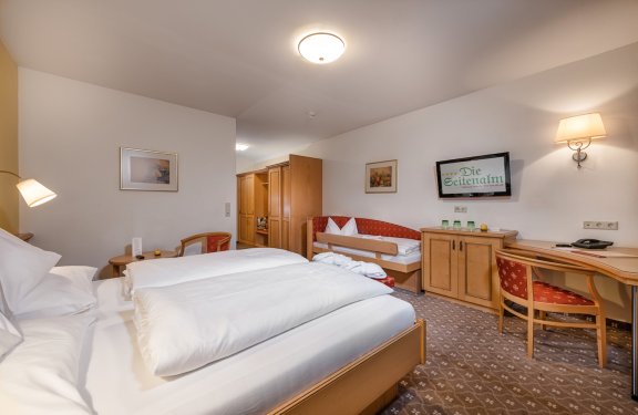 Familienfreundliches Zimmer mit Doppelbett, Schlafsofa und Arbeitsplatz mit TV.