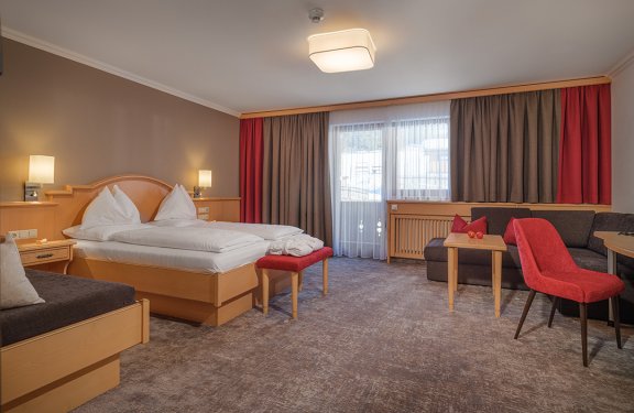 Geräumiges Zimmer mit Doppelbett, Sofaecke und Zugang zum Balkon.