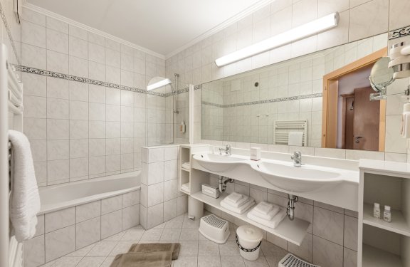 Helles Bad mit Badewanne, Doppelwaschbecken und praktischen Handtuchfächern.